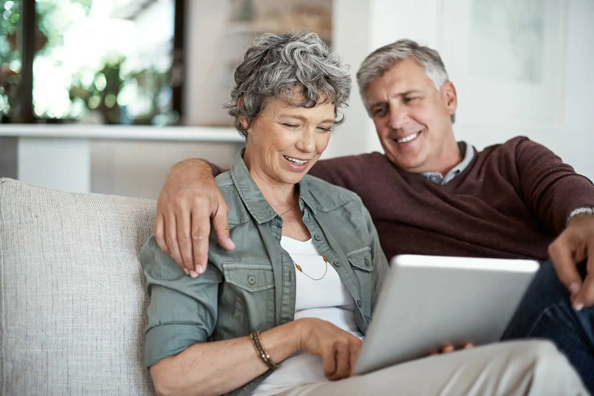 Senior couple relaxing on a couch looking at a tablet